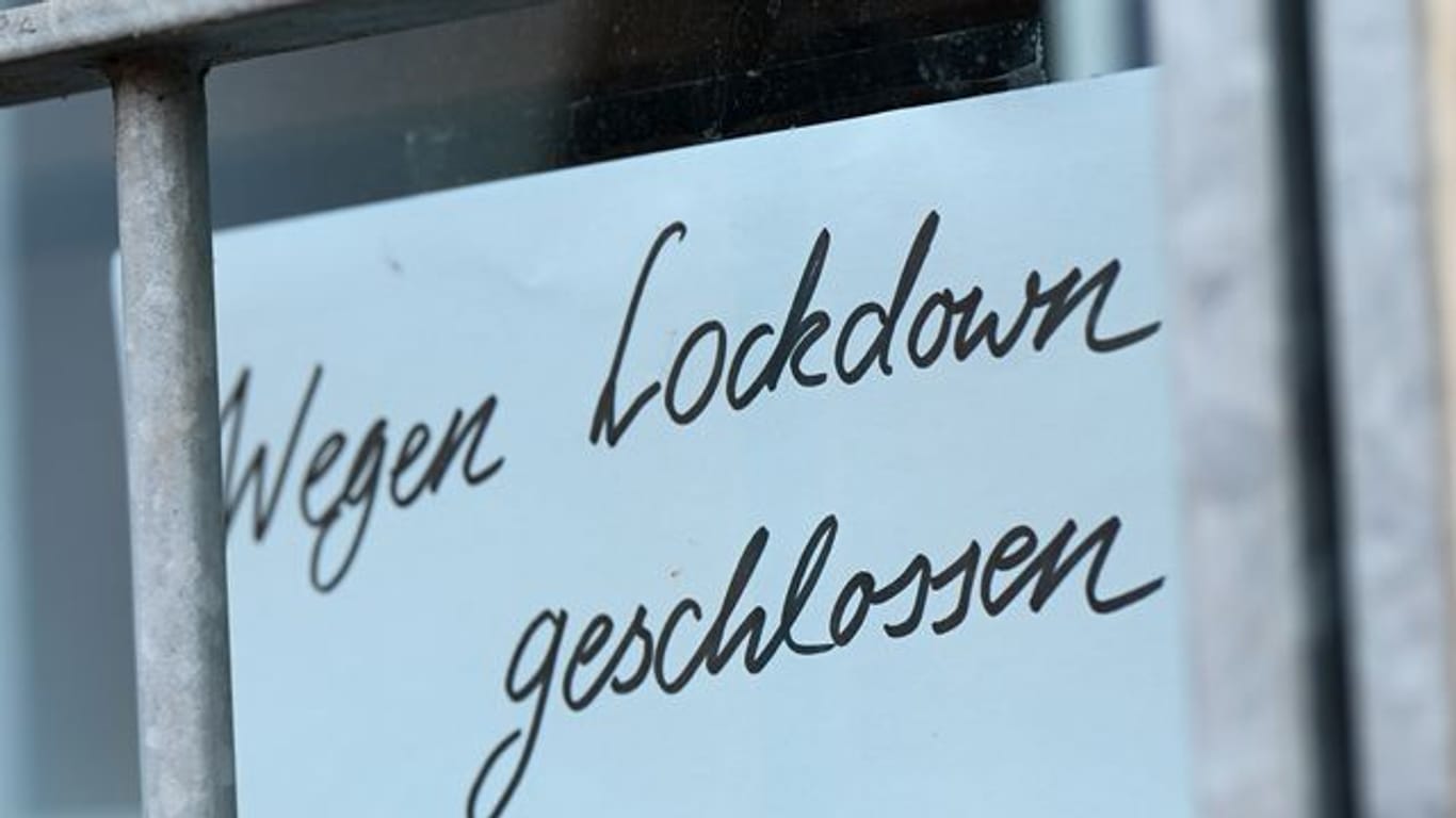 Ein Zettel mit der Aufschrift "Wegen Corona geschlossen" hängt am Schaufenster eines Geschäfts.