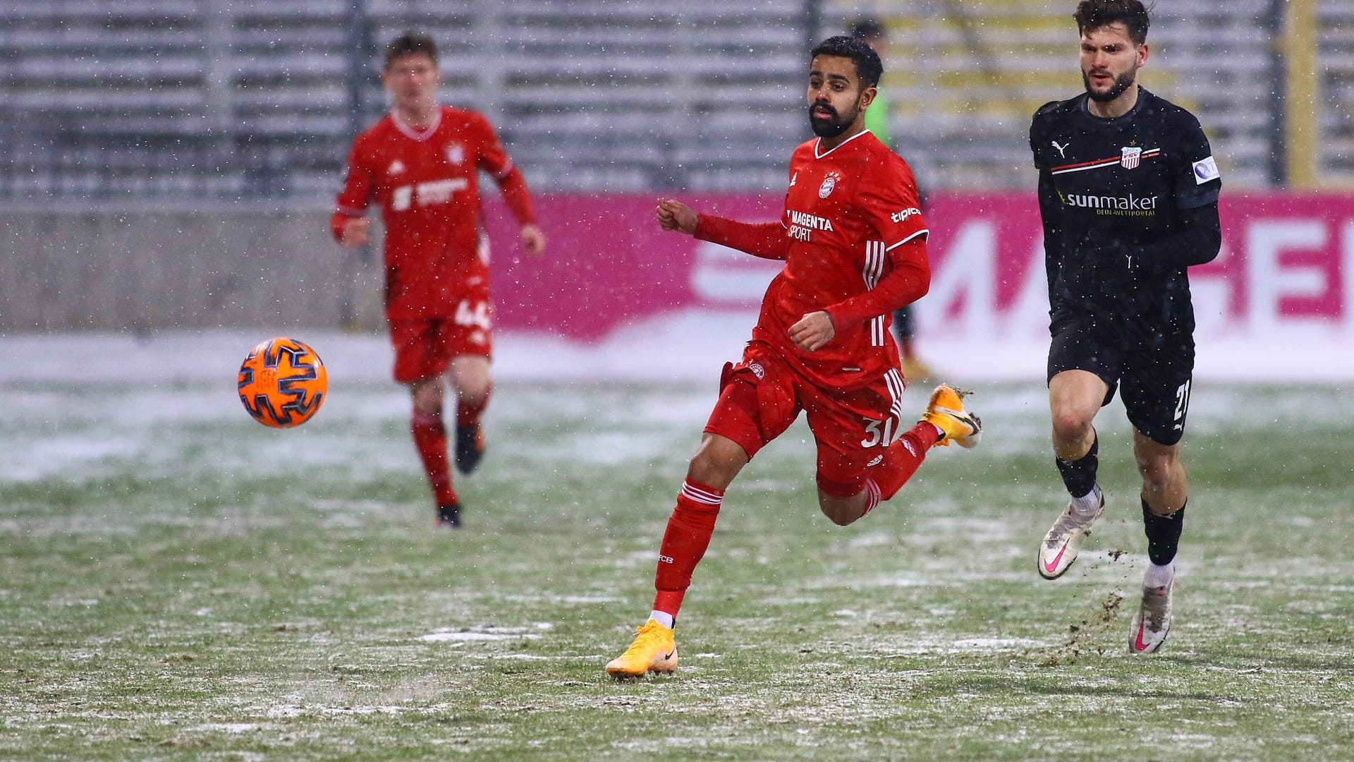 Sarpreet Singh (m.) vom FC Bayern II im Laufduell: Der Platz in München war teilweise vom Schnee bedeckt.