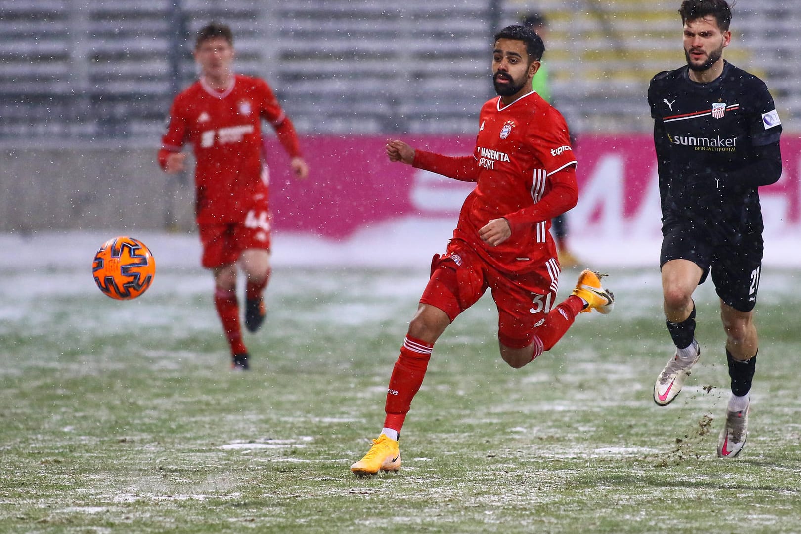 Sarpreet Singh (m.) vom FC Bayern II im Laufduell: Der Platz in München war teilweise vom Schnee bedeckt.