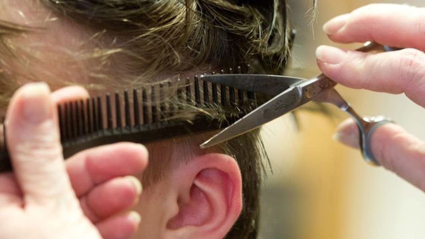 Eine Friseurin schneidet die Haare einer Kundin (Symbolbild): Die angekündigte Öffnung der Friseursalons hat einen Run auf Termine ausgelöst.