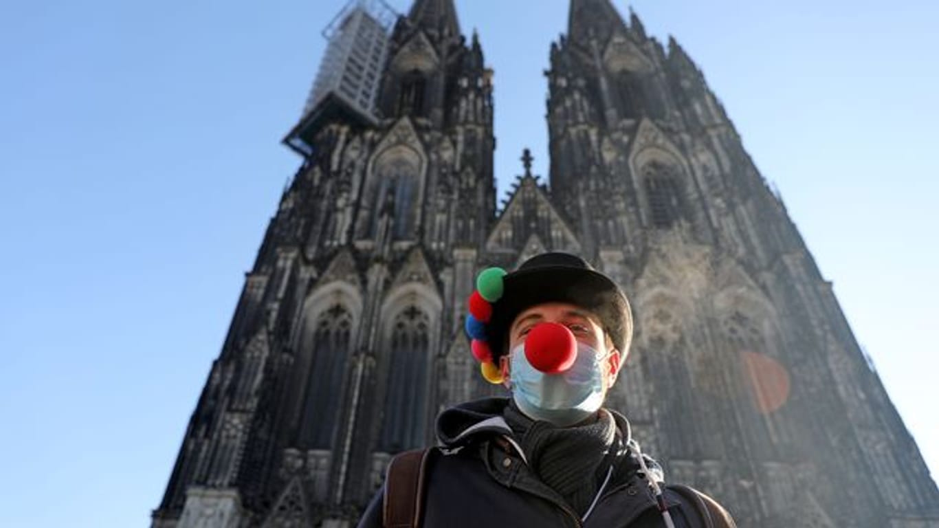 Lorenz steht mit Clownsnase auf der Maske vor dem Kölner Dom.