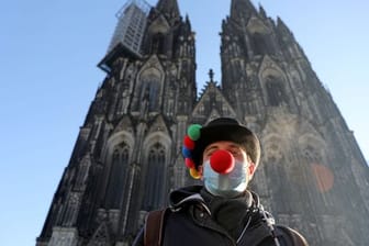 Lorenz steht mit Clownsnase auf der Maske vor dem Kölner Dom.