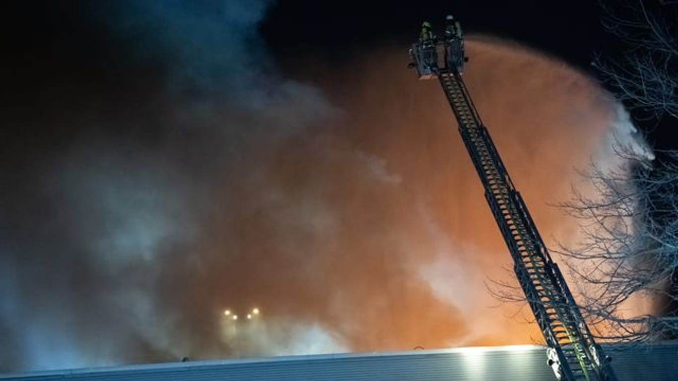 Feuerwehrleute versuchen einen Hallenbrand zu bekämpfen: Aus der Halle sind Schadstoffwolken entwichen.