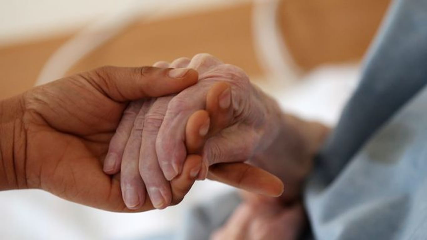 Eine Pflegerin hält in einem Altenheim die Hand einer Bewohnerin (Symbolbild): Die Corona-Fälle in Hamburger Pflegeheimen haben sich halbiert.