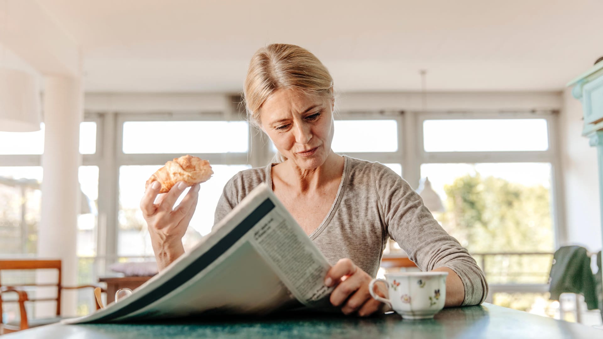 Eine Frau liest beim Frühstück die Zeitung: Die Corona-Pandemie hat uns einige überraschende Schlagzeilen geliefert.