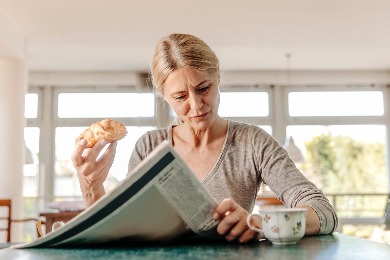 Eine Frau liest beim Frühstück die Zeitung: Die Corona-Pandemie hat uns einige überraschende Schlagzeilen geliefert.