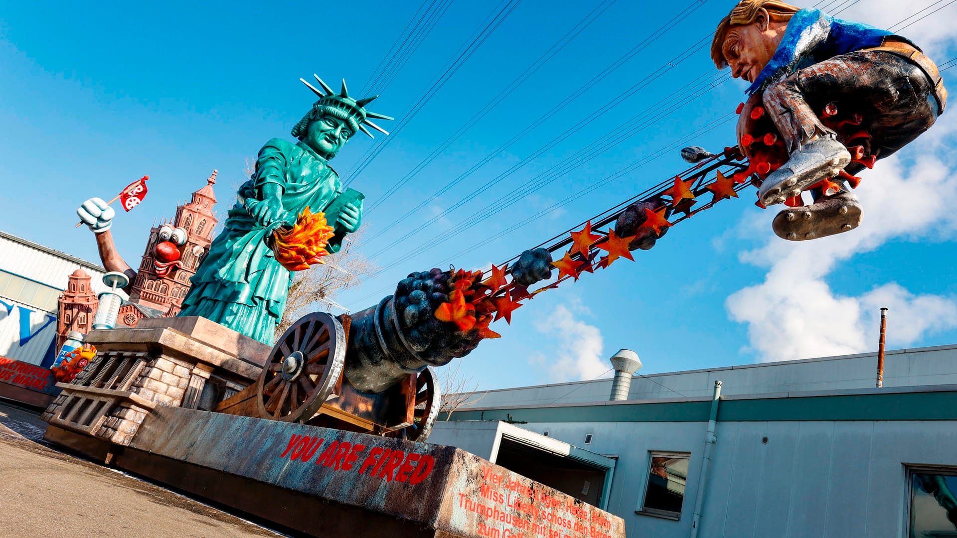 Ein Umzugswagen des Mainzer Carnevals-Vereins thematisiert die Abwahl des US-Präsidenten Donald Trump: Unter dem Motto "You are fired" senkt dabei die Freiheitsstatue ihre Fackel nach unten und entzündet eine Kanone, aus der Donald Trump auf einer Kugel sitzend gefeuert wird. Ein Umzugswagen des Mainzer Carnevals-Vereins thematisiert die Abwahl des US-Präsidenten Donald Trump: Unter dem Motto "You are fired" senkt dabei die Freiheitsstatue ihre Fackel nach unten und entzündet eine Kanone, aus der Donald Trump auf einer Kugel sitzend gefeuert wird.