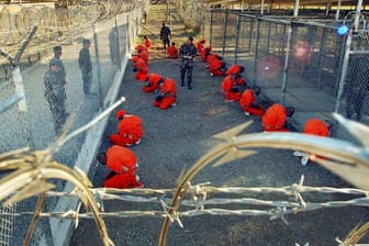 US-Gefangenlager Guantanamo: In orangefarbene Overalls gekleidete Häftlinge knien im Camp X-Ray, einem Teil des Lagers, auf dem Boden.