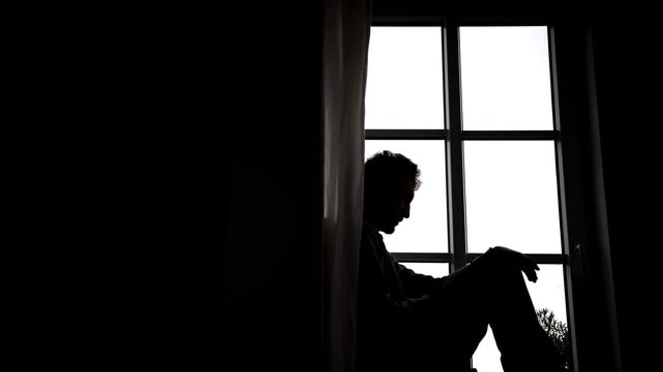 Ein Mann sitzt vor einem Fenster.