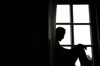 Ein Mann sitzt vor einem Fenster.