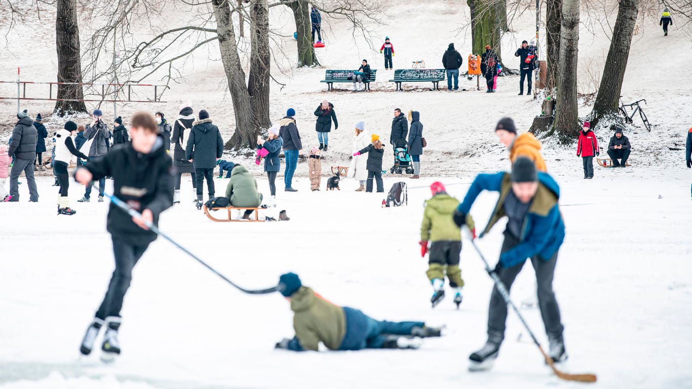 Menschen nutzen das Eis zum Schlitten fahren und Eishockey spielen: Auch der Weißensee ist zugefroren.