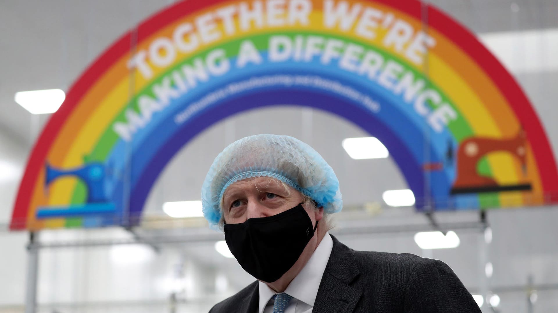 Der englische Premierminister Boris Johnson mit Maske vor einem Banner mit der Aufschrift "Gemeinsam können wir etwas verändern" (Archivbild). Er will eine einheitliche Impfstrategie der G7-Länder.