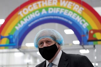 Der englische Premierminister Boris Johnson mit Maske vor einem Banner mit der Aufschrift "Gemeinsam können wir etwas verändern" (Archivbild). Er will eine einheitliche Impfstrategie der G7-Länder.