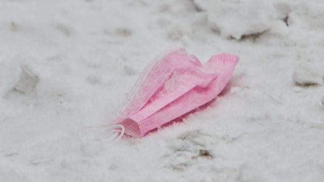 Eine pinke Maske liegt im Schnee.