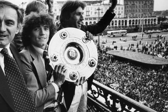 Kevin Keegan (M) feiert mit Meisterschale in Händen zwischen HSV-Trainer Branco Zebec (l) und Abwehrspieler Manfred Kaltz den Erfolg.