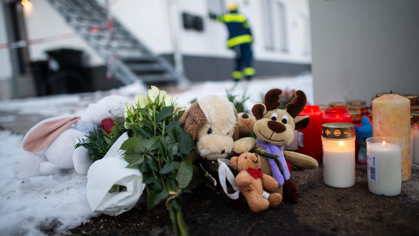 Kuscheltiere und Kerzen liegen vor dem Haus, in dem ein Mann offenbar seine Familie und sich getötet hat: Die Ermittlungen stehen vor dem Abschluss.