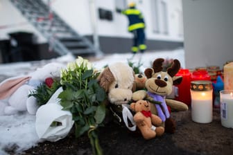 Kuscheltiere und Kerzen liegen vor dem Haus, in dem ein Mann offenbar seine Familie und sich getötet hat: Die Ermittlungen stehen vor dem Abschluss.