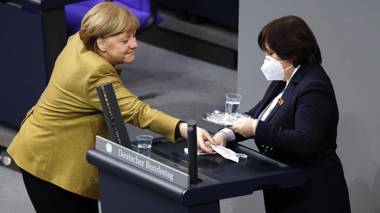 Upsala: Eine Saaldienerin reinigt schon das Pult für die nächste Rednerin, da holt Angela Merkel schnell noch ihre vergessene Maske ab.