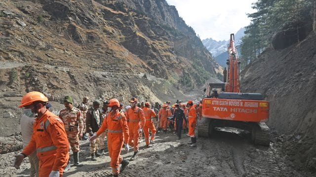 Mitarbeiter der National Disaster Response Force räumen Trümmer weg, nachdem ein Teil des Nanda Devi Gletschers abgebrochen und in einen Fluss gestürzt war. Mitarbeiter der National Disaster Response Force räumen Trümmer weg, nachdem ein Teil des Nanda Devi Gletschers abgebrochen und in einen Fluss gestürzt war.
