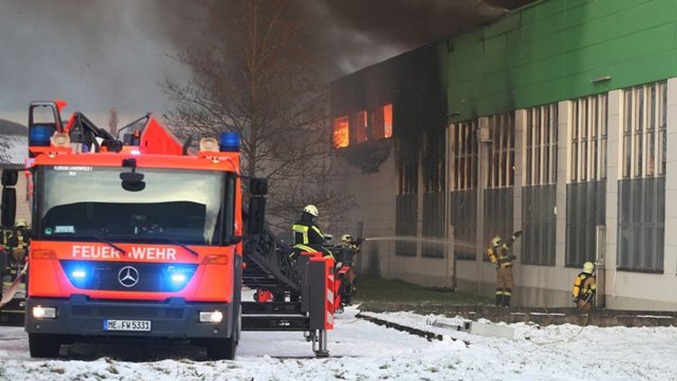 Feuerwehrleute bekämpfen den Großbrand in der Lagerhalle in Hilden: Immer wieder war das Löschwasser gefroren.