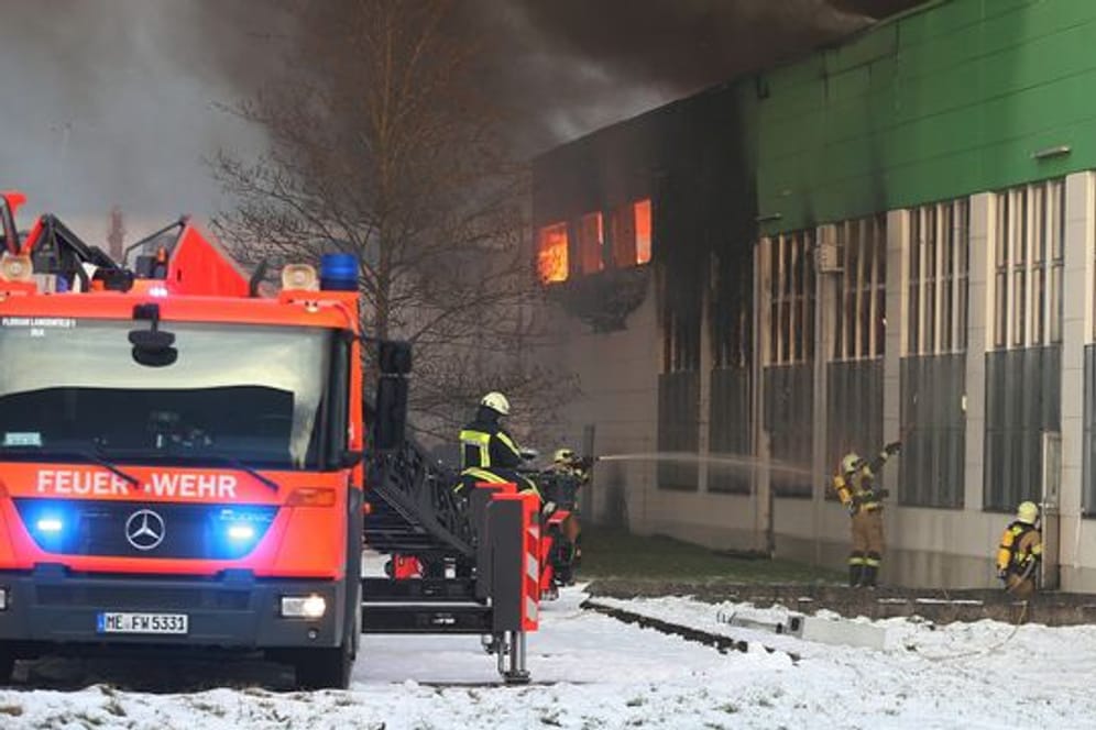 Feuerwehrleute bekämpfen den Großbrand in der Lagerhalle in Hilden: Immer wieder war das Löschwasser gefroren.