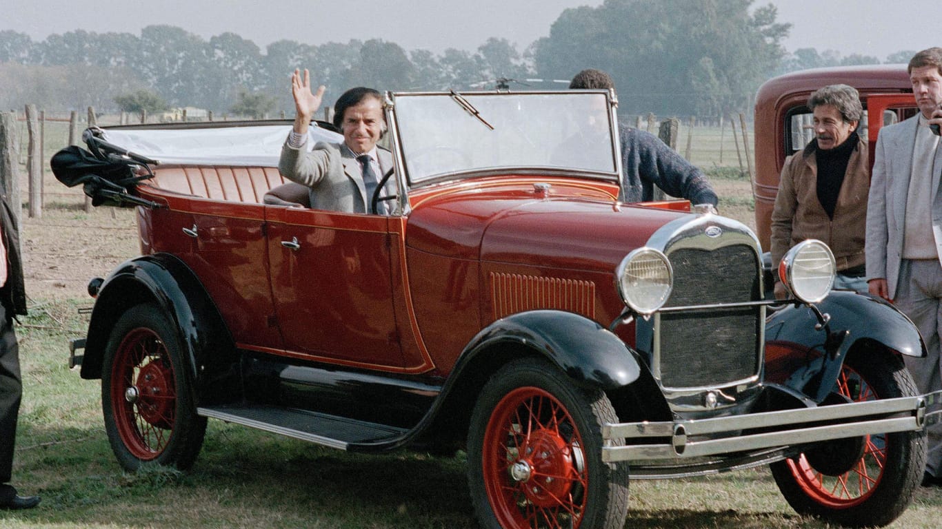 Carlos Menem winkt 1989 aus einem Oldtimer. Der ehemalige argentinische Staatschef hatte eine große Liebe für Autos.