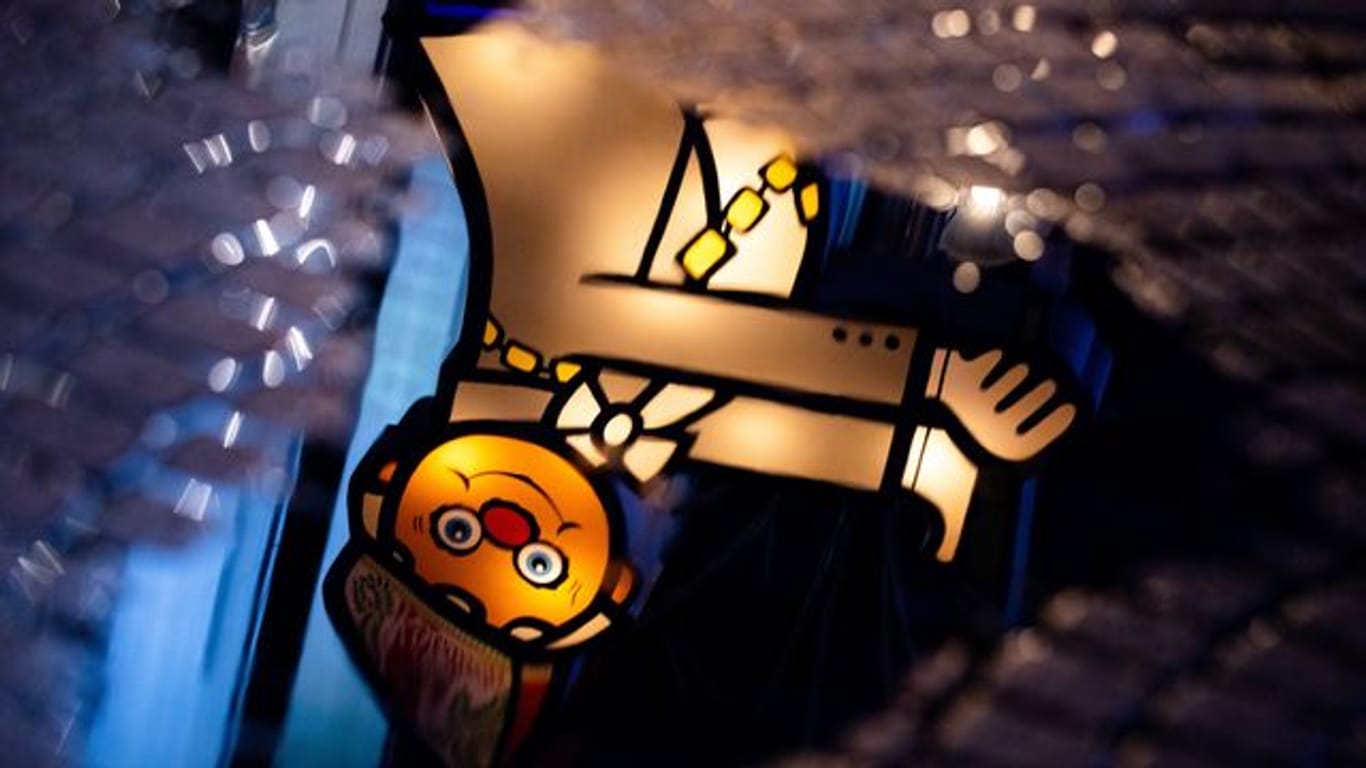 Eine beleuchtete Karnevalsfigur spiegelt sich in einer Pfütze in der Kölner Innenstadt (Symbolbild): Ersatzprogramme sollen den Karnevalisten den Rosenmontag trotz Pandemie versüßen.