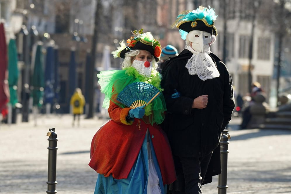 Zwei Menschen in Kostümen gehen durch die Kölner Innenstadt: Kostümieren ist erlaubt, in großer Runde Karneval feiern jedoch verboten.
