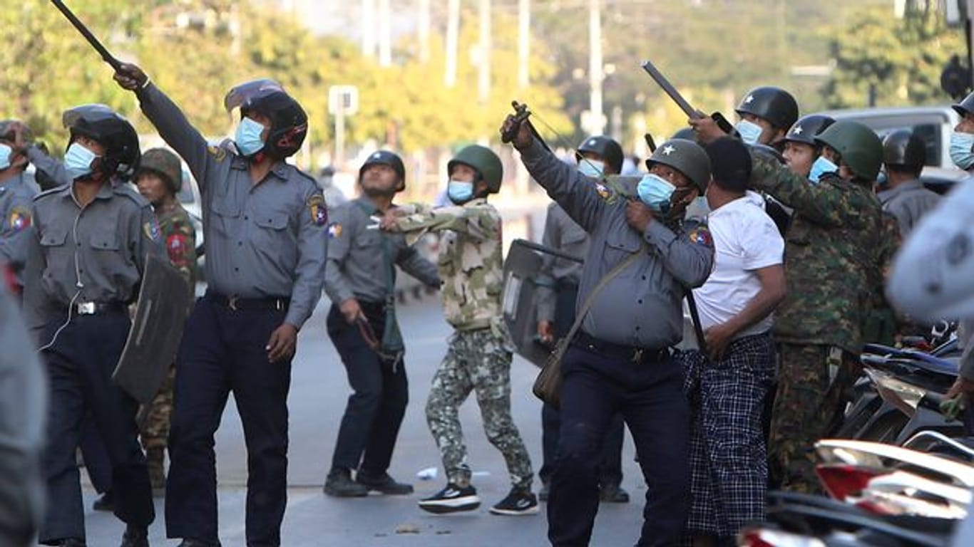 Ein Polizist schießt in Mandalay mit einer Steinschleuder.
