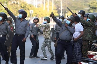 Ein Polizist schießt in Mandalay mit einer Steinschleuder.