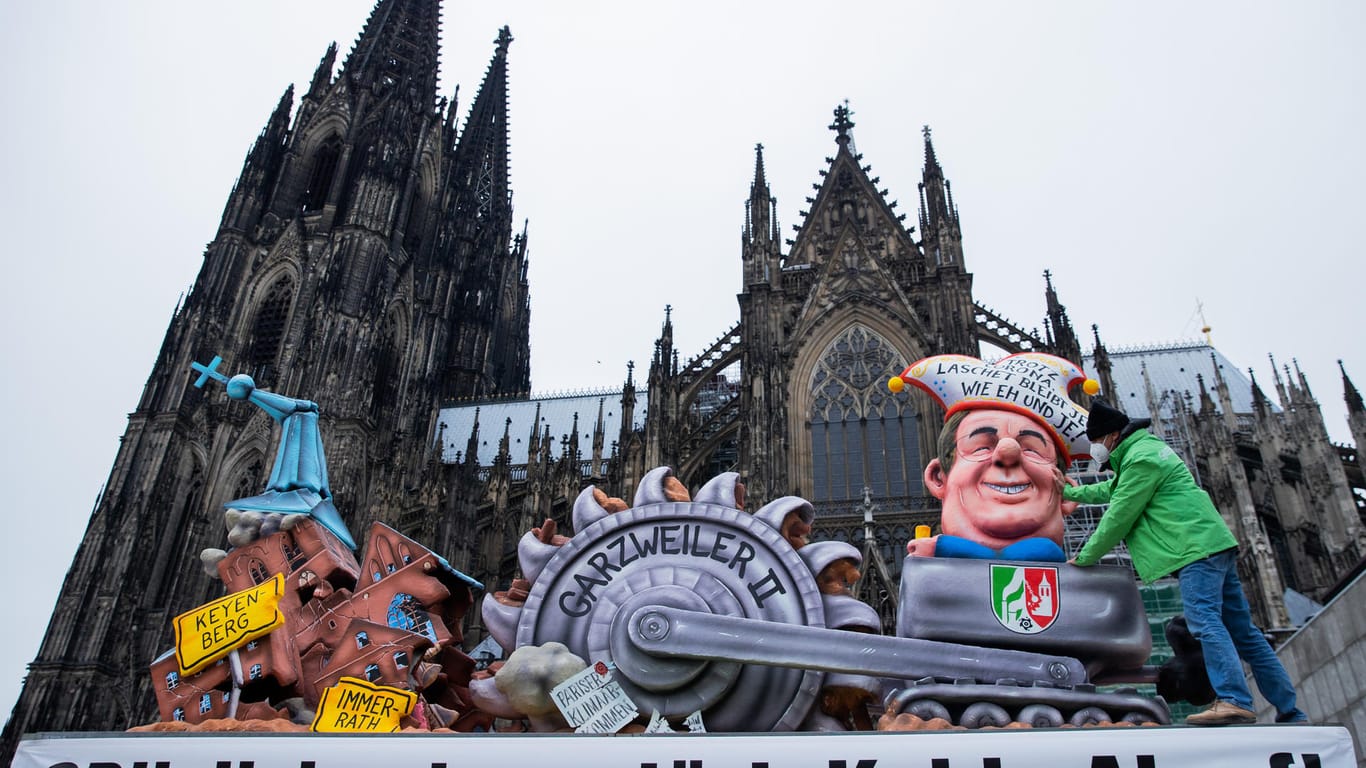 Ein Karnevalswagen, der die Kirche des Dorfes Keyenberg, einen Braunkohlebagger und eine Karikatur des NRW-Ministerpräsidenten Armin Laschet zeigt, steht auf dem Roncalliplatz: Greenpeace protestiert mit dem Karnevalswagen gegen die Klimapolitik von Laschet.