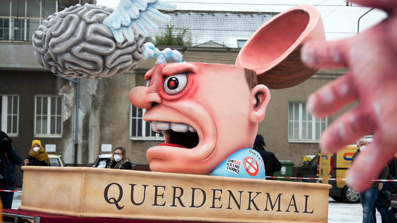 Ein Mottowagen mit einer Figur mit aufgeklapptem Schädel, darüber ein Gehirn mit Flügeln, und der Aufschrift "Querdenkmal": Trotz Lockdowns rollten am Rosenmontag einige Mottowagen durch Düsseldorf.