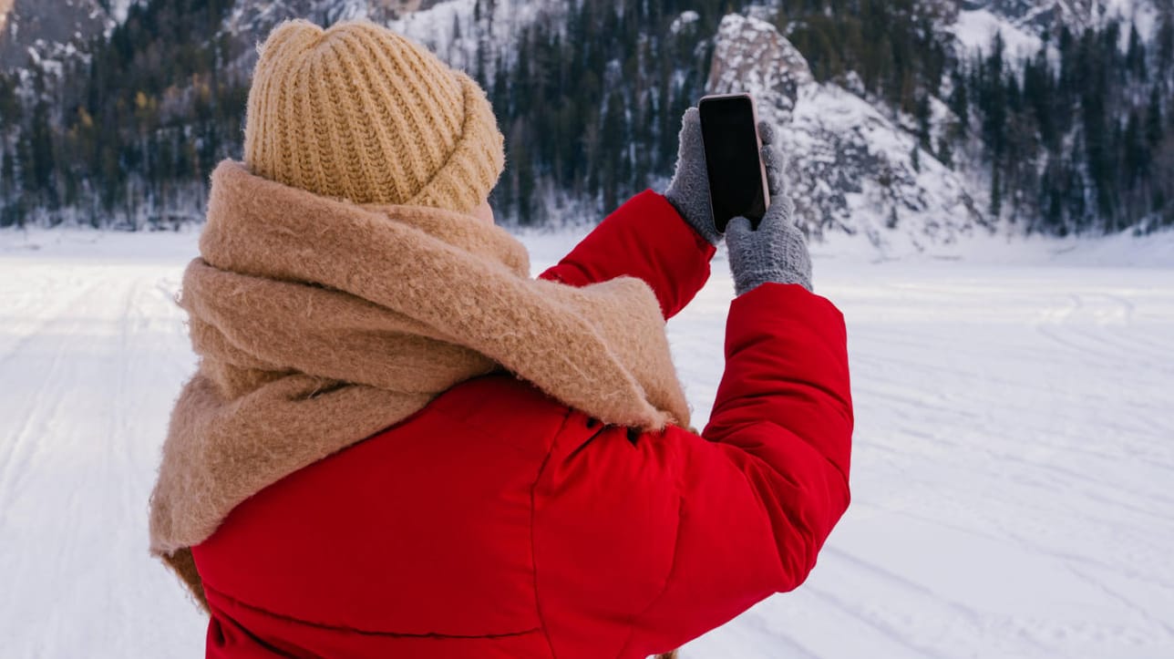 Eine Frau mit Smartphone im Winter (Symbolbild): Bei Kälte verhalten sich Smartphones plötzlich anders – warum eigentlich? Eine Frau mit Smartphone im Winter (Symbolbild): Bei Kälte verhalten sich Smartphones plötzlich anders – warum eigentlich?