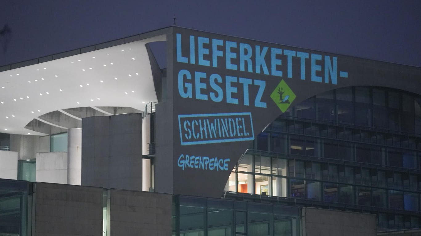 Bei einer Greenpeace-Aktion zum Lieferkettengesetz wird der Spruch "Lieferkettengesetz. Schwindel" an die Außenfassade des Bundeskanzleramts projiziert.