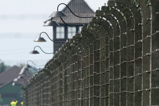 Stacheldrahtzäune und ein Wachturm auf dem Gelände des ehemaligen Vernichtungslagers Auschwitz-Birkenau.