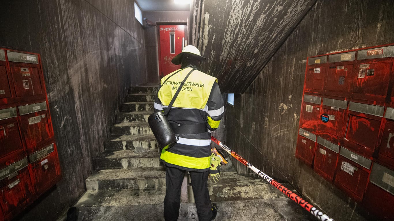 Ein Feuerwehrmann steht nach einem Brand im vollkommen verrußten Treppenhaus eines Studentenwohnheims im Münchner Stadtteil Freimann: Nach einem Brand schwebt mindestens eine Person in Lebensgefahr.