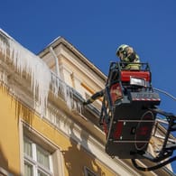 Feuerwehrleute entfernen in Bautzen Eiszapfen von einem Dach (Symbolbild): Auch in Düsseldorf hielten abstürzende Eisgebilde die Feuerwehr auf Trab.