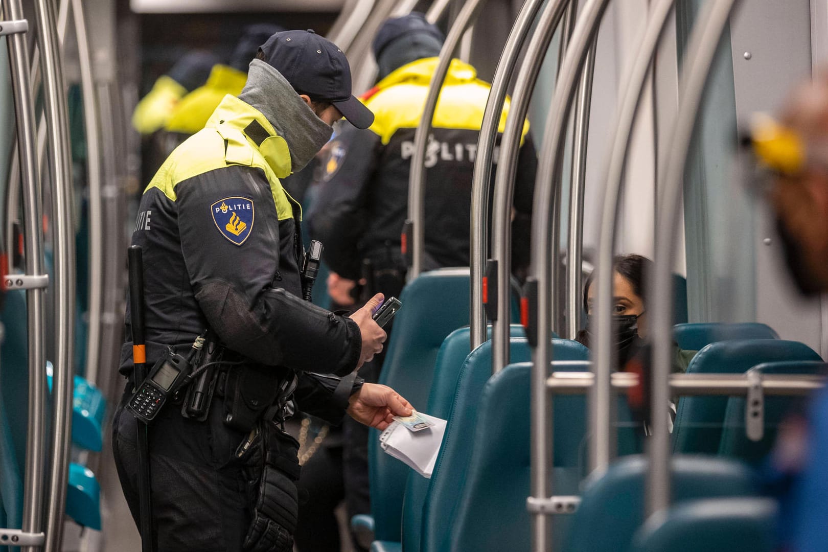 Niederländische Polizisten kontrollieren die Ausgangssperre in der Straßenbahn: Wer keine schriftlichen Belege zur Aufhebung der Ausgangssperre parat hat, muss 95 Euro bezahlen.