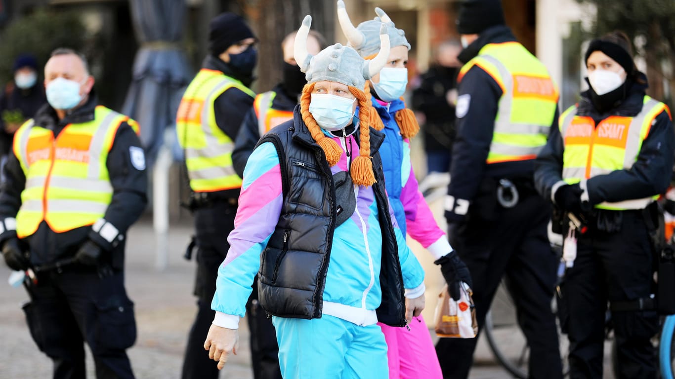 Karnevalisten mit Maske gehen an Mitarbeitern des Ordnungsamtes vorbei: In der Stadt wurde die Einhaltung der Corona-Regeln kontrolliert.
