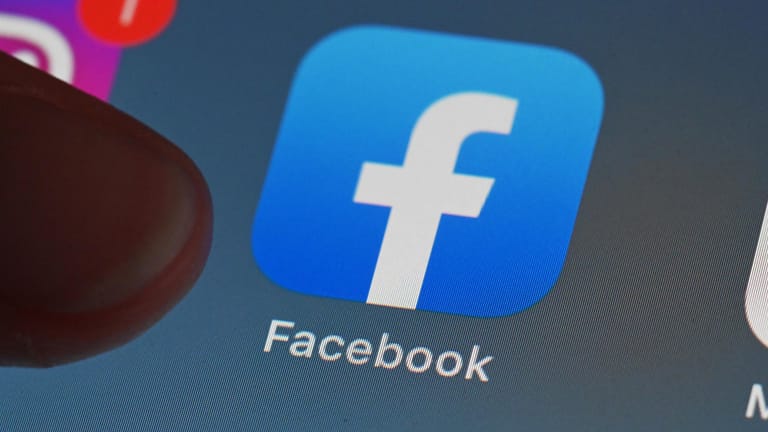 Eine Person zeigt auf einem Tablet auf die Facebook App: In Italien soll das Netzwerk eine Millionenstrafe zahlen.