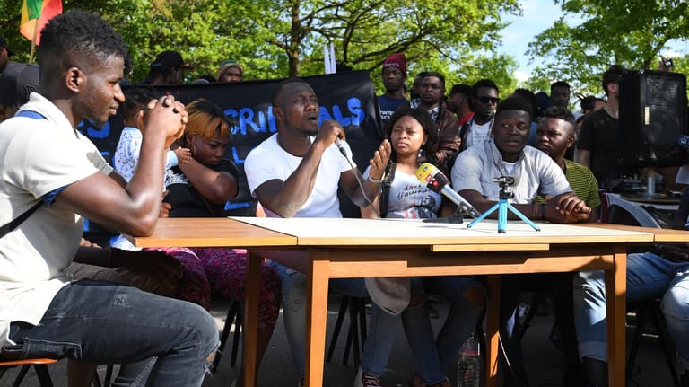 Pressekonferenz der LEA-Bewohner: Rechts am Tisch im weißen T-Shirt sitzt Alassa Mfouapon.