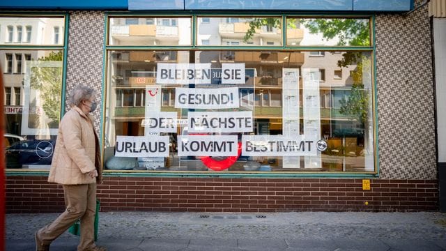 Eine Passantin mit Maske geht an einem Reisebüro vorbei. Eine Passantin mit Maske geht an einem Reisebüro vorbei.