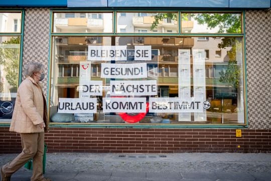 Eine Passantin mit Maske geht an einem Reisebüro vorbei.