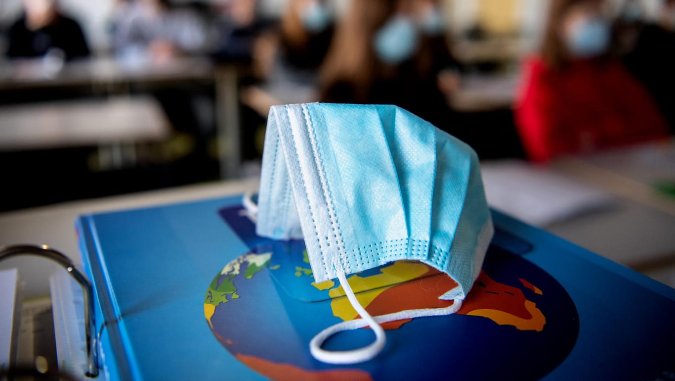 Eine Schutzmaske liegt in einer Schulklasse: Das Robert-Koch-Institut hat am Donnerstag wieder mehr als 10.000 Corona-Neuinfektionen gemeldet.