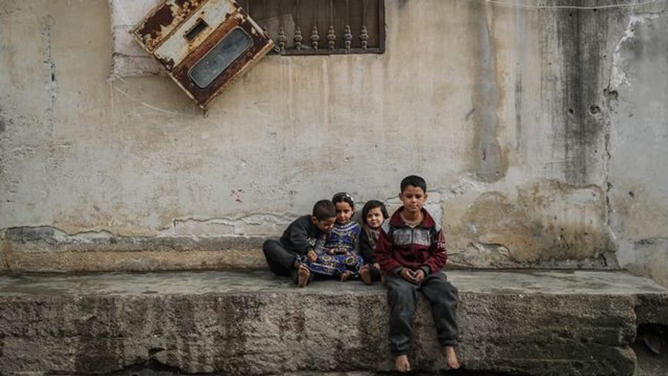 Syrische Kinder sitzen zwischen beschädigten Gebäuden im Dorf Afes.