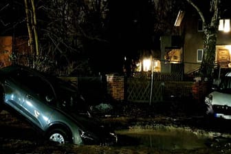 Ein Auto ist zur Hälfte in ein Wasserloch eingesunken: In einer Straße in Hermsdorf entstand ein Krater durch einen Bruch in einer Wasserleitung.