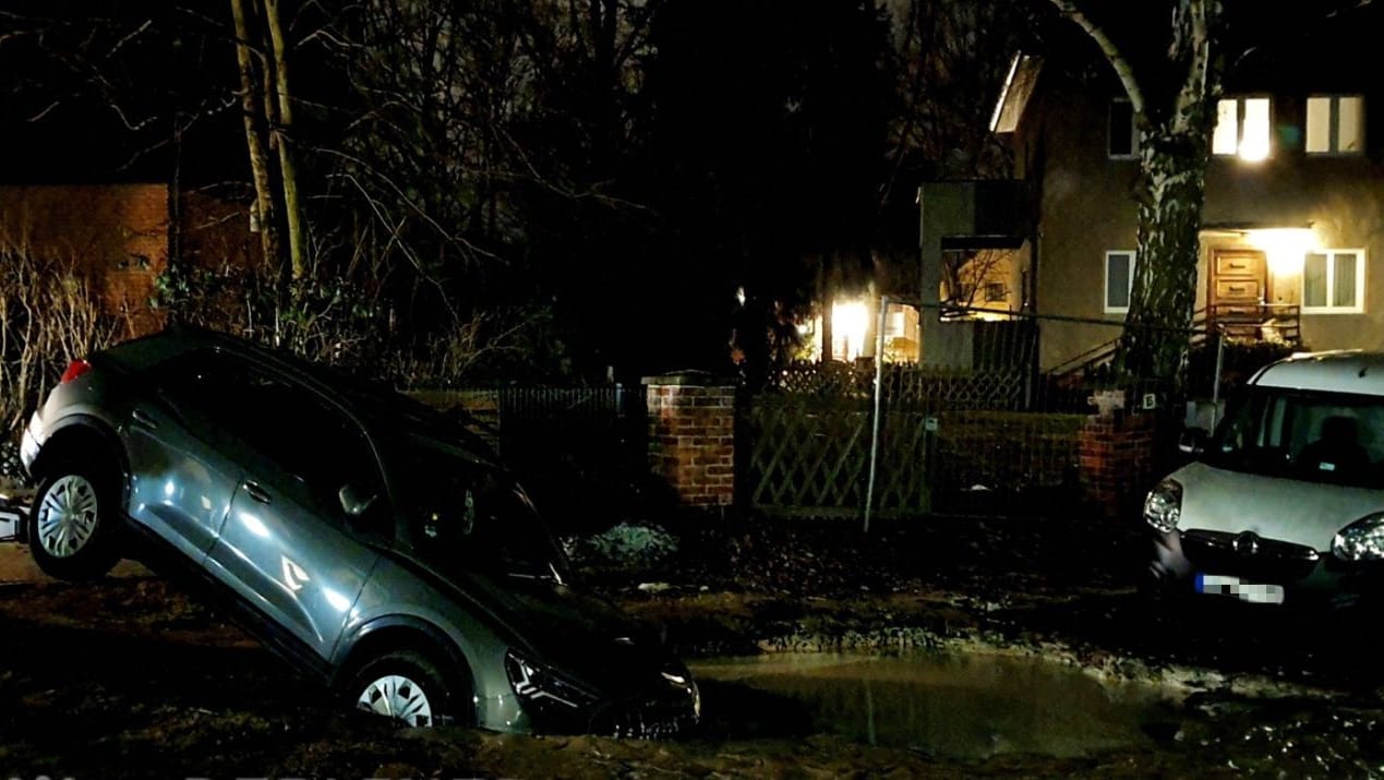 Ein Auto ist zur Hälfte in ein Wasserloch eingesunken: In einer Straße in Hermsdorf entstand ein Krater durch einen Bruch in einer Wasserleitung.