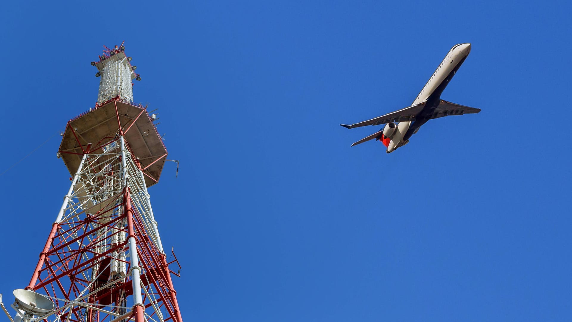 Ein Flugzeug fliegt an einem Sendemast vorbei (Symbolbild): Die französische Luftfahrtbehörde warnt davor, dass 5G-Geräte Flugzeuge bei der Landung stören könnten.