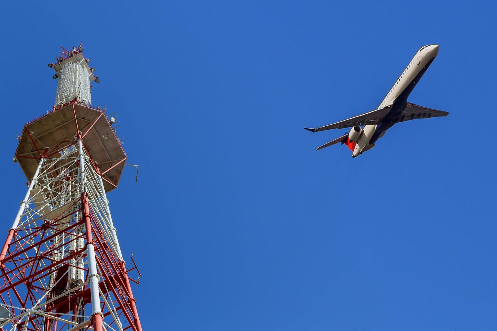 Ein Flugzeug fliegt an einem Sendemast vorbei (Symbolbild): Die französische Luftfahrtbehörde warnt davor, dass 5G-Geräte Flugzeuge bei der Landung stören könnten.