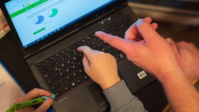 Ein Junge nutzt zusammen mit seinem Vater einen Laptop für den Heimunterricht. Ein Junge nutzt zusammen mit seinem Vater einen Laptop für den Heimunterricht.